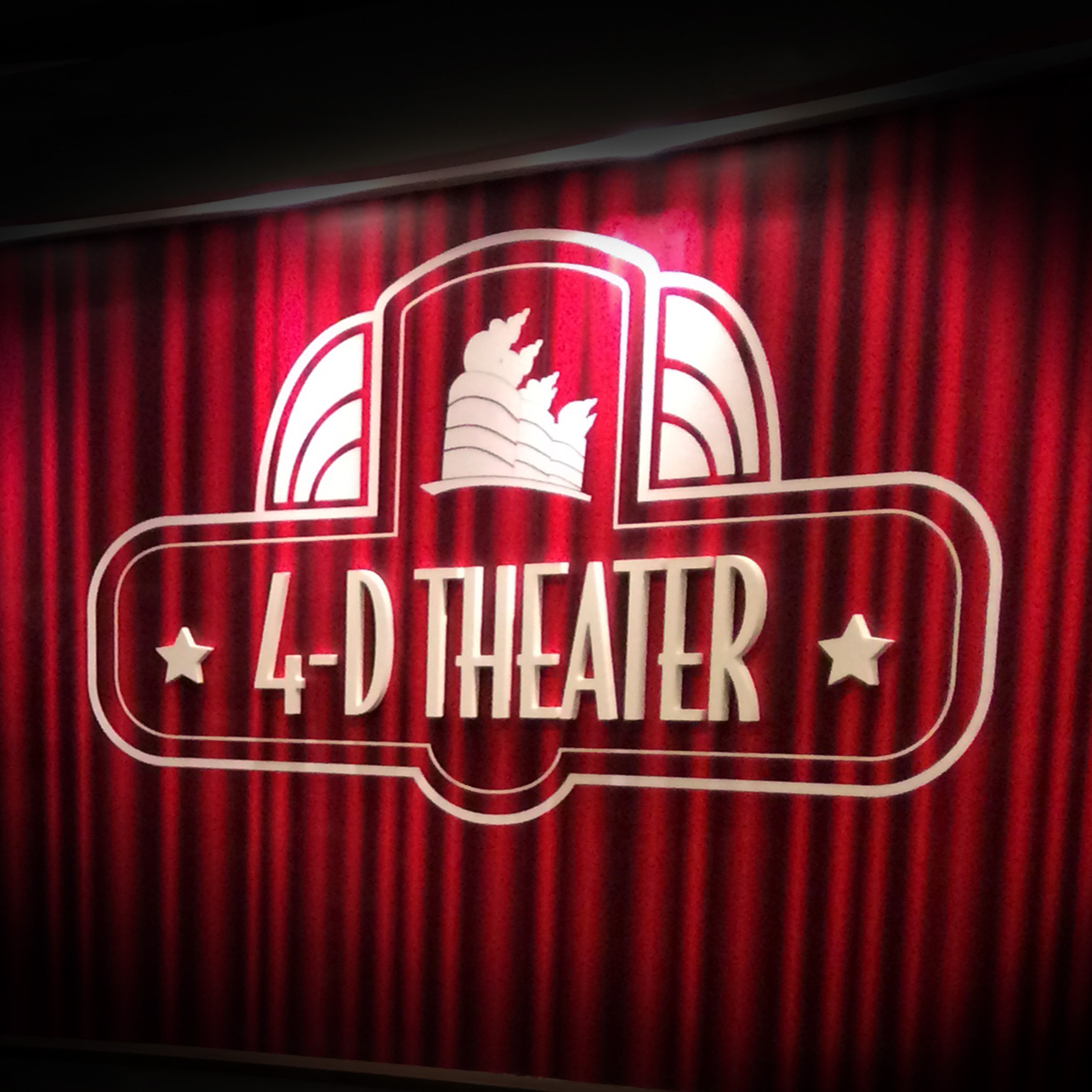 the queen mary 4d theater logo sign on red curtain graphic